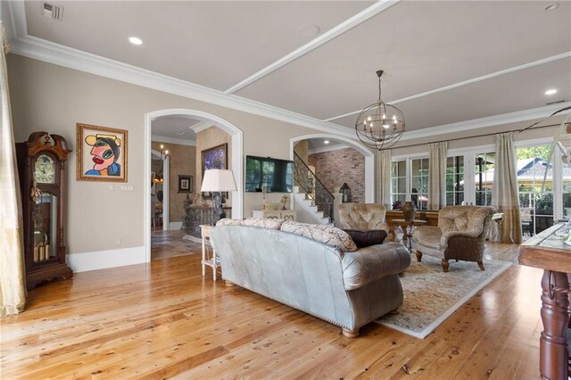 living room with a notable chandelier, crown molding, and light hardwood / wood-style floors