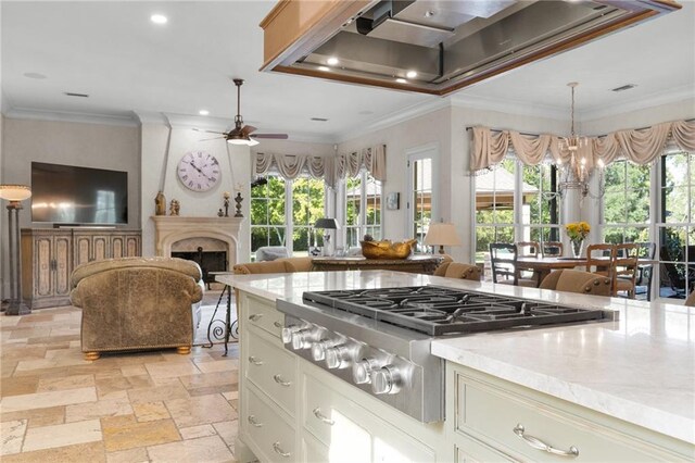 kitchen featuring light tile patterned flooring, ceiling fan with notable chandelier, light stone counters, and a healthy amount of sunlight