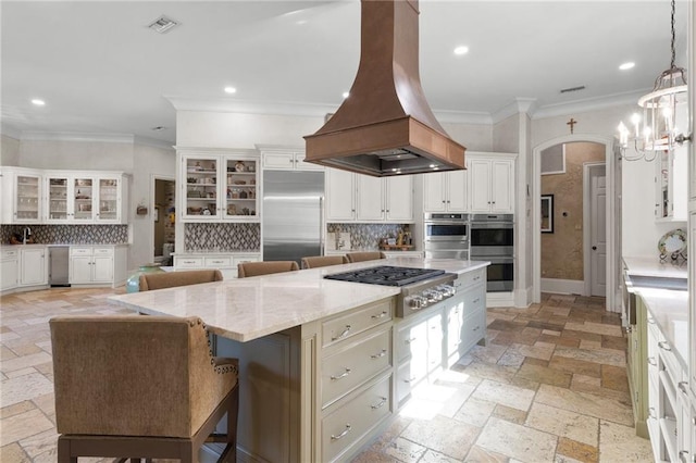 kitchen with a kitchen island, glass insert cabinets, a breakfast bar area, island exhaust hood, and stainless steel appliances