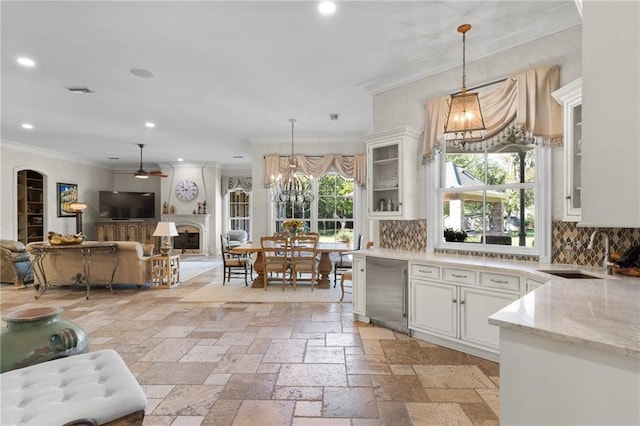 kitchen featuring hanging light fixtures, a sink, glass insert cabinets, and white cabinets