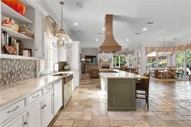 kitchen with sink, a notable chandelier, a center island, and a healthy amount of sunlight