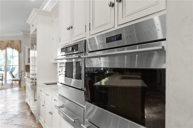 kitchen with crown molding, stainless steel double oven, and white cabinets