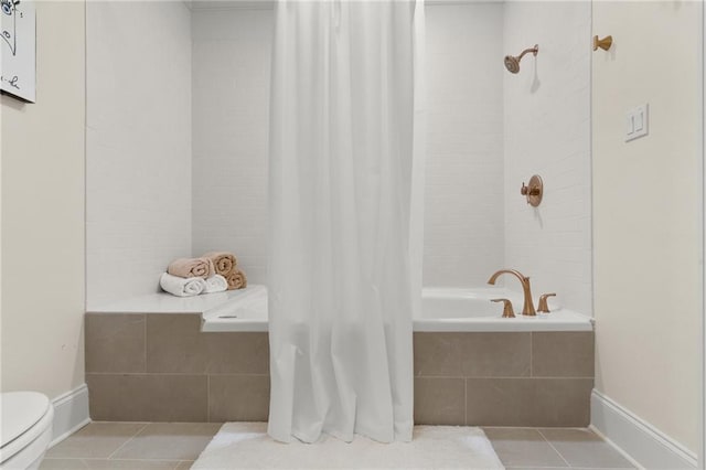 bathroom featuring baseboards, tiled shower / bath, toilet, and tile patterned floors