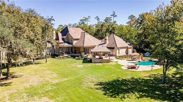 rear view of property featuring a gazebo, an outdoor pool, a patio, and a yard