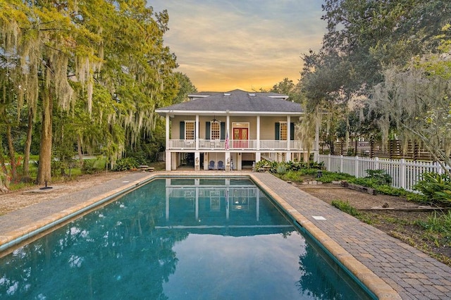 back house at dusk with a fenced in pool