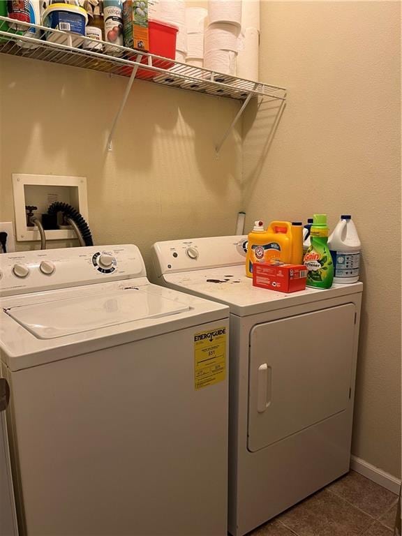 washroom featuring washer and dryer, laundry area, dark tile patterned floors, and baseboards