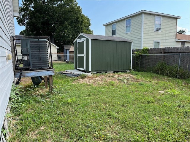 view of yard featuring cooling unit, a fenced backyard, an outdoor structure, and a storage shed