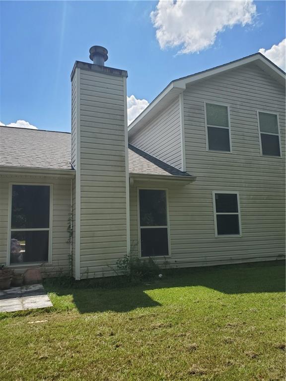 1122 Lori Dr, Slidell, LA 70461 - rear view of property with a chimney, a yard, and roof with shingles