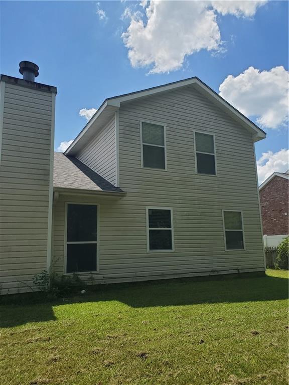 1122 Lori Dr, Slidell, LA 70461 - back of property featuring a lawn, a chimney, and a shingled roof