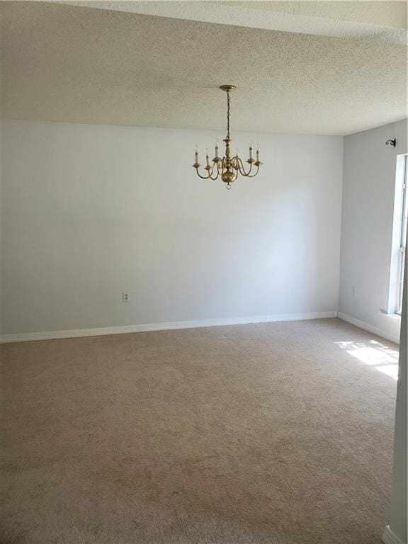 unfurnished room featuring carpet, a chandelier, and a textured ceiling