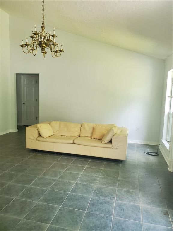 unfurnished living room with vaulted ceiling, dark tile patterned flooring, and a notable chandelier