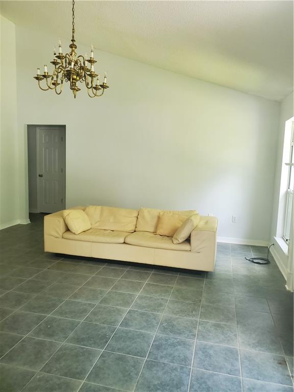 1122 Lori Dr, Slidell, LA 70461 - living area featuring a chandelier, baseboards, lofted ceiling, and dark tile patterned floors