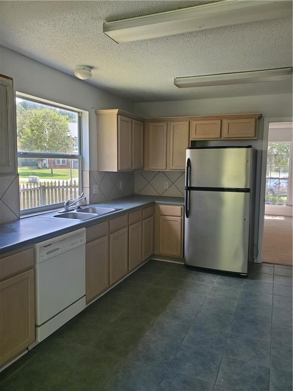 1122 Lori Dr, Slidell, LA 70461 - kitchen with freestanding refrigerator, dishwasher, a sink, backsplash, and a textured ceiling