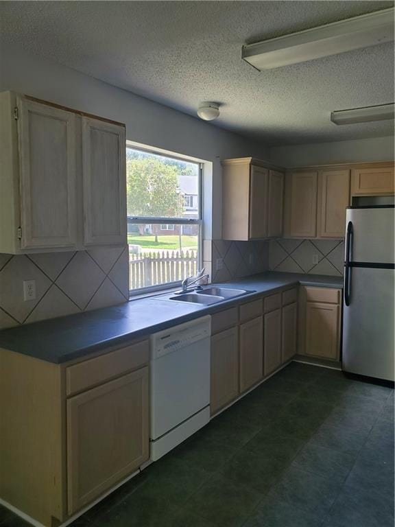 kitchen featuring white dishwasher, stainless steel fridge, sink, backsplash, and light brown cabinetry