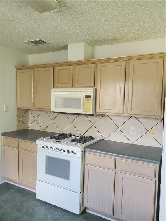 1122 Lori Dr, Slidell, LA 70461 - kitchen with white appliances, light brown cabinetry, decorative backsplash, a textured ceiling, and dark countertops