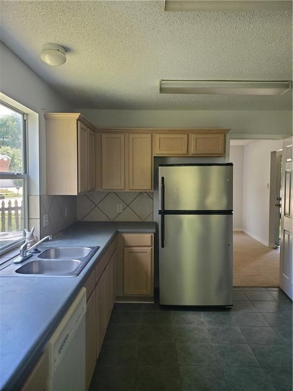 1122 Lori Dr, Slidell, LA 70461 - kitchen with freestanding refrigerator, a sink, dishwasher, light brown cabinets, and decorative backsplash