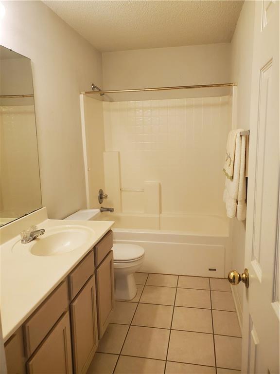 1122 Lori Dr, Slidell, LA 70461 - bathroom featuring a textured ceiling, toilet, vanity, tile patterned floors, and bathing tub / shower combination