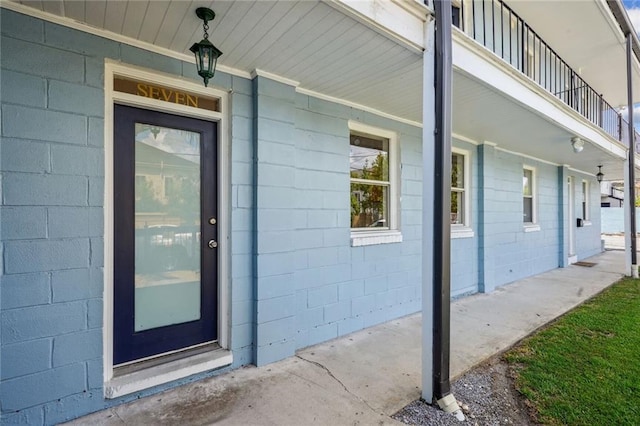 view of exterior entry with a balcony and covered porch