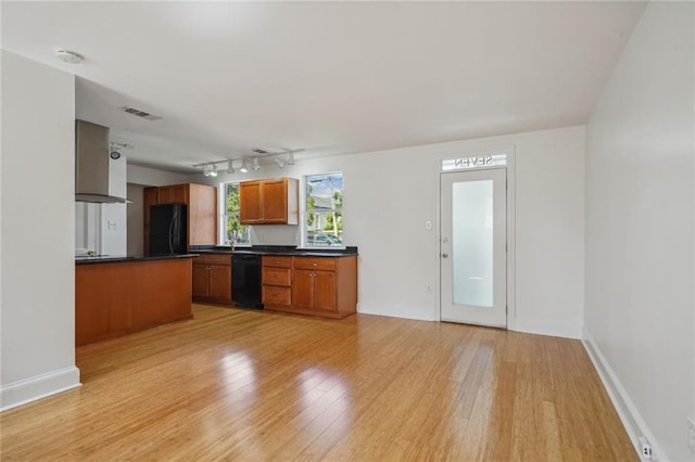 kitchen with light hardwood / wood-style floors, track lighting, wall chimney range hood, and black appliances