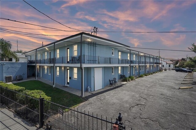 property exterior at dusk featuring a balcony and central AC