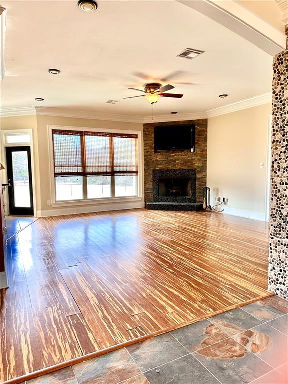 unfurnished living room featuring crown molding, ceiling fan, a fireplace, and hardwood / wood-style floors