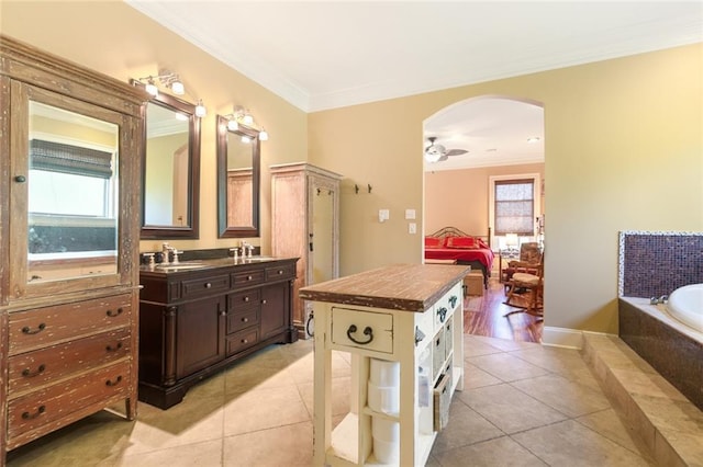 bathroom featuring vanity, ceiling fan, tiled tub, crown molding, and tile patterned floors