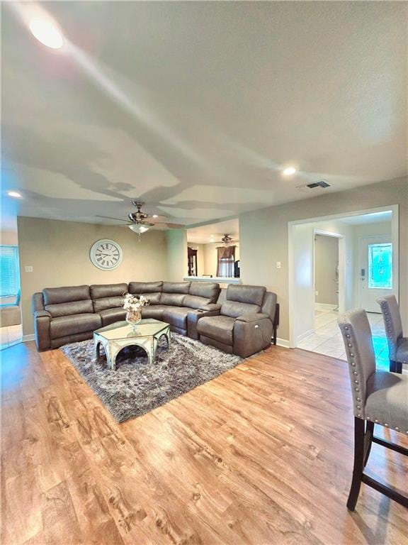 living room with a wealth of natural light, light hardwood / wood-style flooring, and ceiling fan