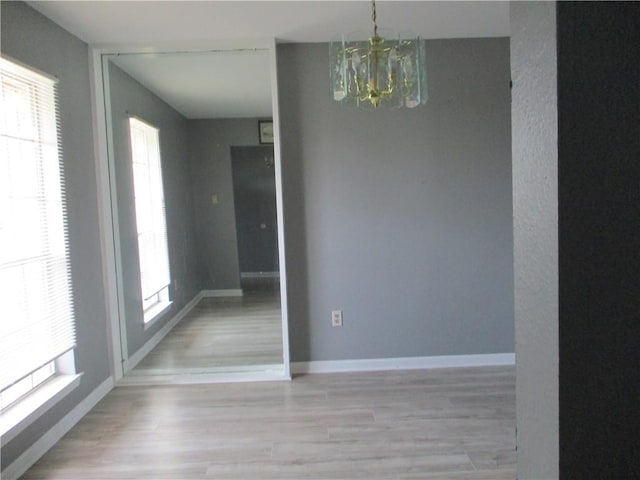 empty room featuring light hardwood / wood-style flooring, a healthy amount of sunlight, and a chandelier