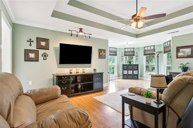 living room with a raised ceiling, ceiling fan, ornamental molding, and hardwood / wood-style flooring