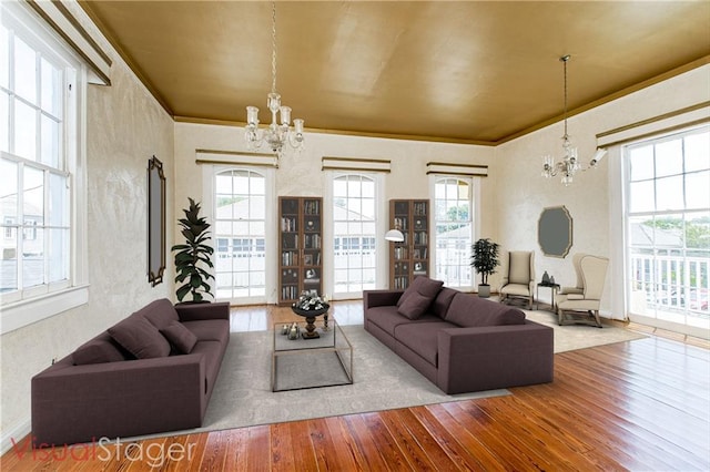 living room featuring wood-type flooring, crown molding, and an inviting chandelier