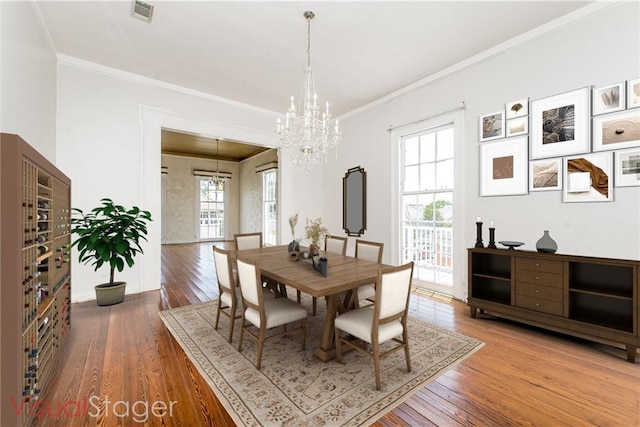 dining room with wood-type flooring, a healthy amount of sunlight, and a notable chandelier