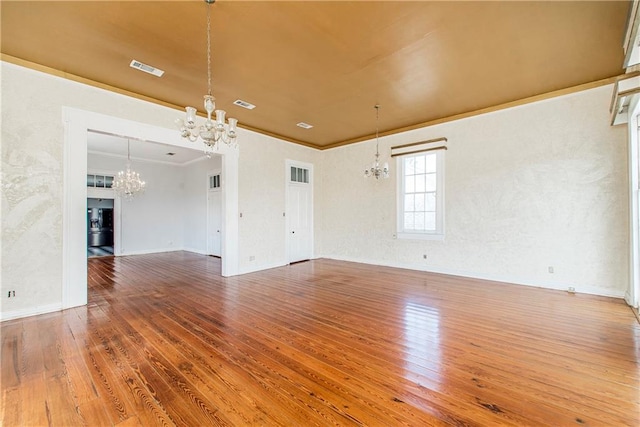 unfurnished living room with ornamental molding, hardwood / wood-style floors, and an inviting chandelier