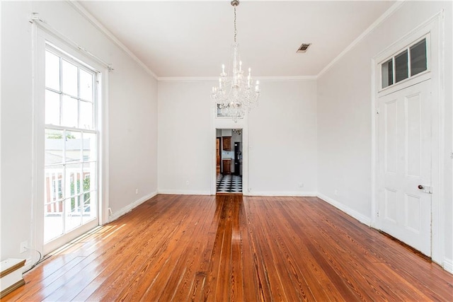 unfurnished dining area with hardwood / wood-style flooring, crown molding, and a notable chandelier