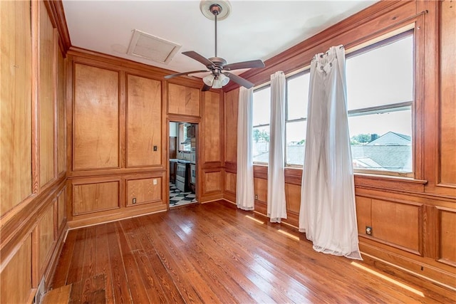 empty room featuring hardwood / wood-style floors, wood walls, and ceiling fan