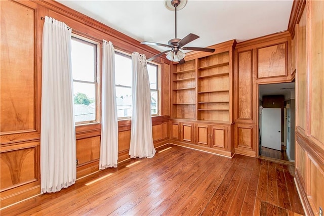 unfurnished living room with hardwood / wood-style floors, ceiling fan, and built in shelves