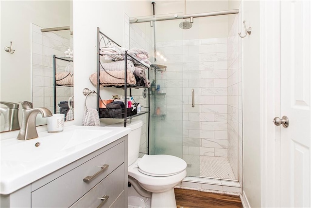 bathroom featuring vanity, hardwood / wood-style flooring, toilet, and a shower with shower door