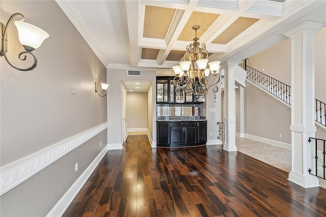 living room featuring decorative columns, a chandelier, dark wood-type flooring, and crown molding