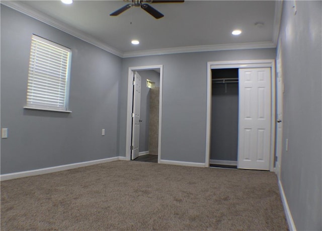 unfurnished bedroom with ornamental molding, dark colored carpet, ceiling fan, and a closet