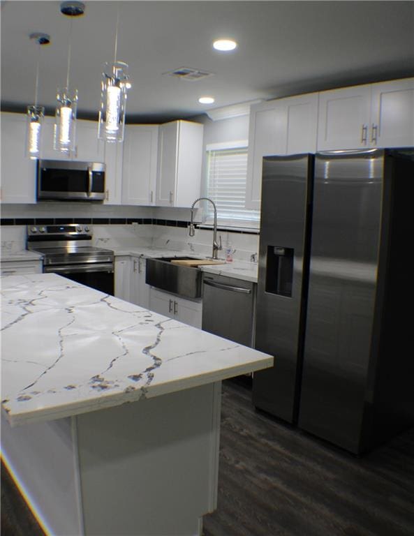 kitchen with white cabinets, light stone countertops, stainless steel appliances, decorative light fixtures, and sink