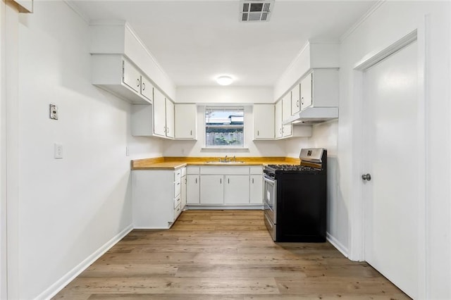 kitchen with light wood-type flooring, stainless steel gas range oven, sink, and white cabinets