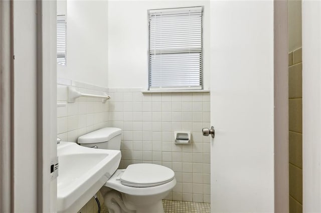 bathroom featuring tile patterned floors, toilet, plenty of natural light, sink, and tile walls