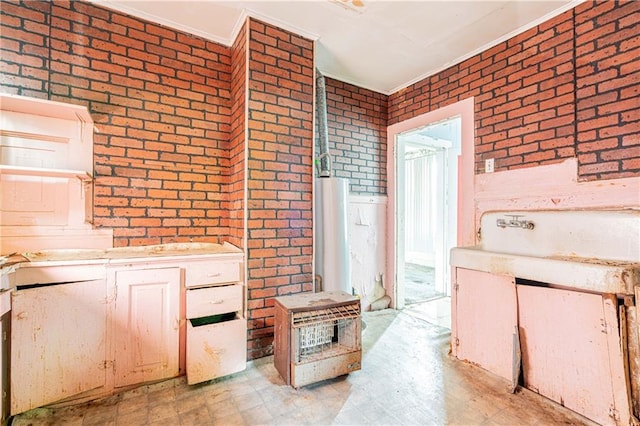 kitchen featuring brick wall, ornamental molding, and light tile patterned flooring