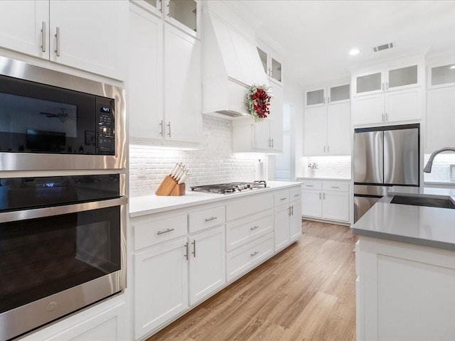 kitchen featuring light hardwood / wood-style floors, appliances with stainless steel finishes, white cabinetry, and tasteful backsplash