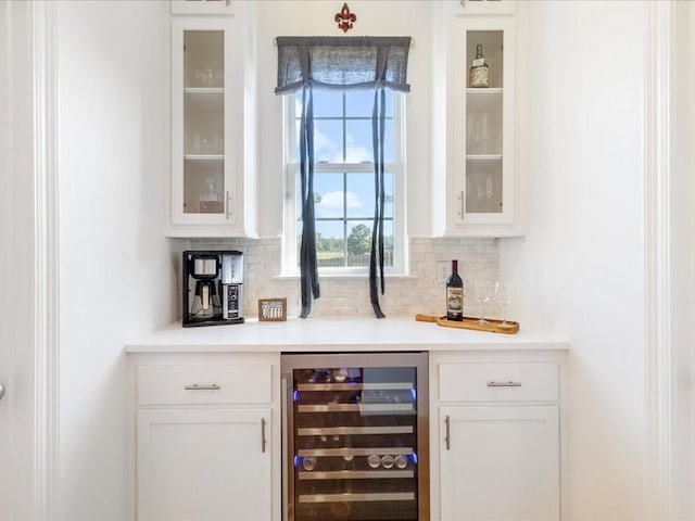 bar featuring beverage cooler, backsplash, and white cabinets