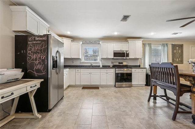 kitchen featuring ceiling fan, stainless steel appliances, white cabinetry, and light tile patterned flooring