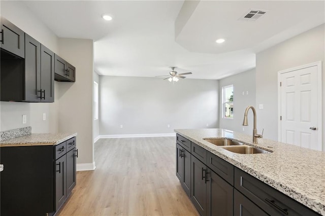 kitchen featuring light hardwood / wood-style flooring, light stone counters, sink, and ceiling fan