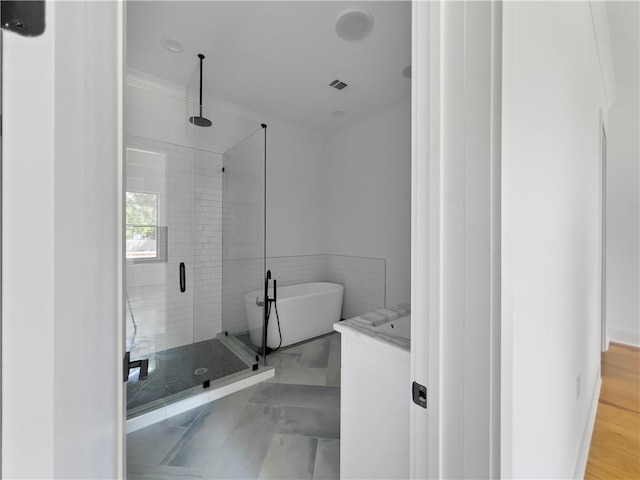 bathroom featuring crown molding, wood-type flooring, and plus walk in shower