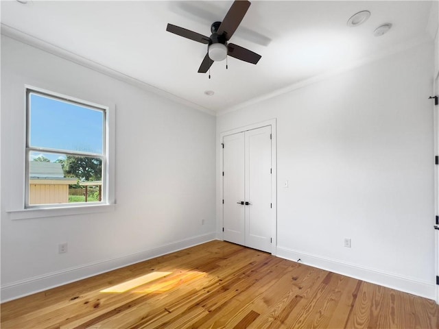 spare room with baseboards, crown molding, light wood-style flooring, and ceiling fan