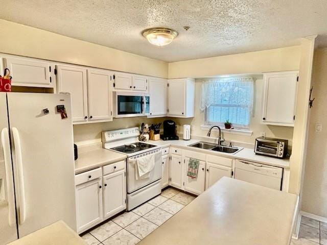 kitchen featuring sink, white appliances, light tile patterned floors, and white cabinets