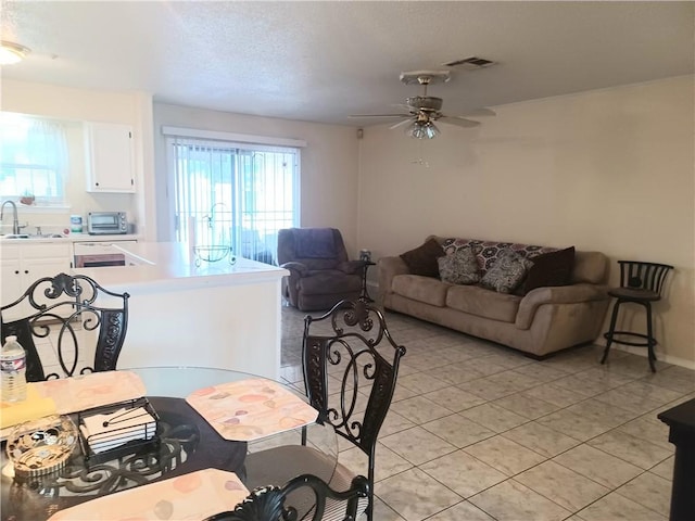 tiled living room with ceiling fan and sink